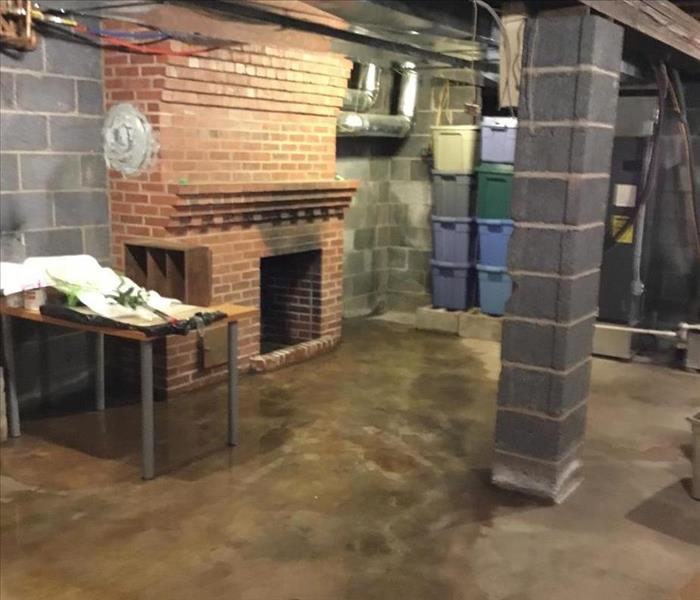 wet concrete basement floor, brick fireplace and cinder block column