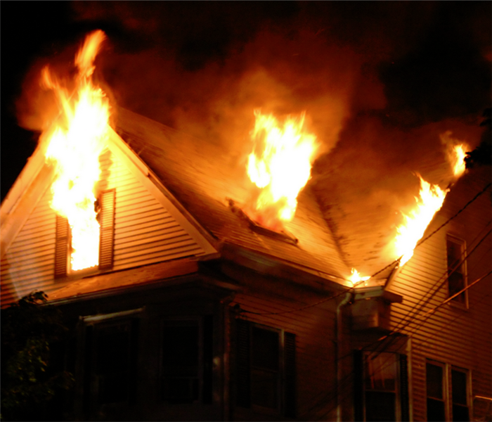 fire bursting through the windows of a house on fire