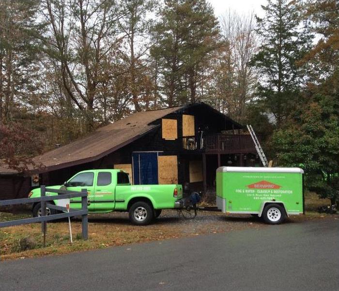 SERVPRO truck with a trailer in front of a fire damaged home