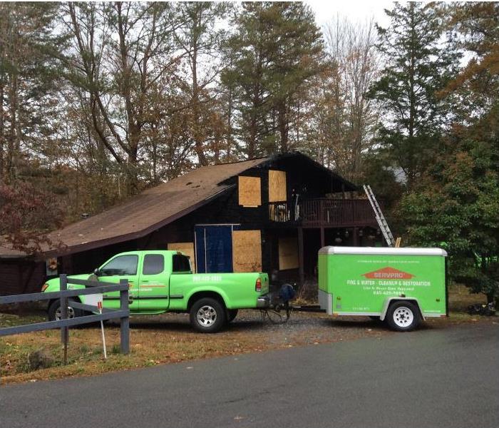 SERVPRO truck with a trailer in front of a fire damaged home
