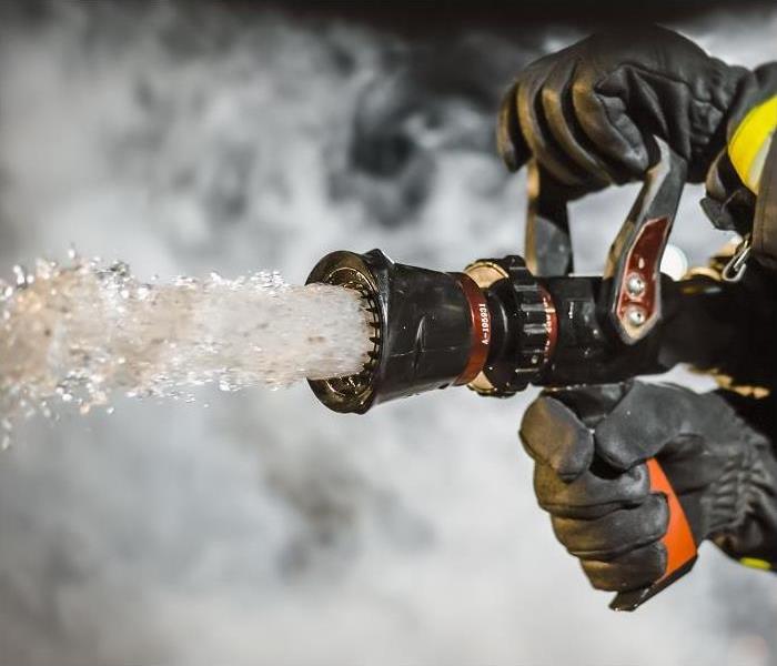 close-up of fireman holding fire hose; water coming out